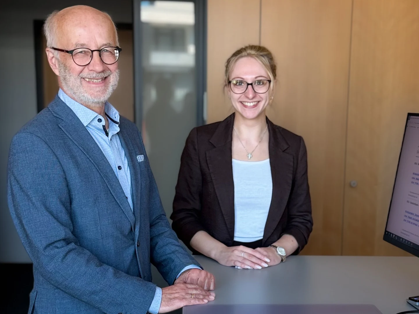 Ein Kollege und eine Kollegin der Sparkasse an Volme und Ruhr stehen im Büro des Bereichs Recht