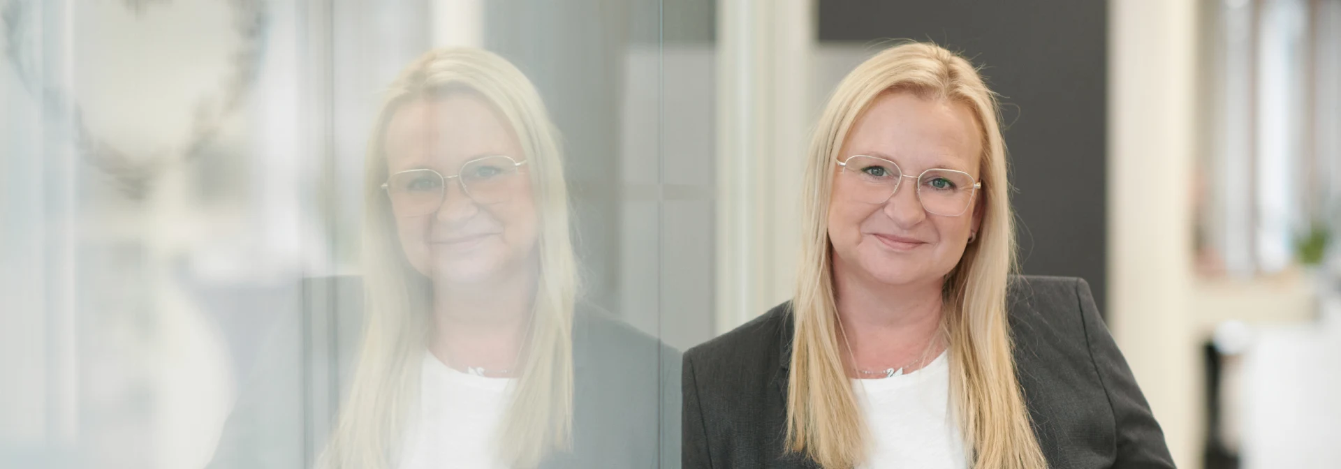 Portrait einer Beraterin der Vereinten Volksbank vor einer Glaswand in der Filiale