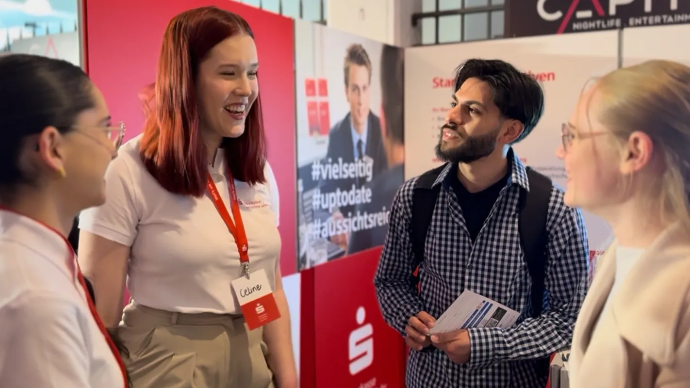 Zwei Azubis im Gespräch mit interessierten Schüler:innen