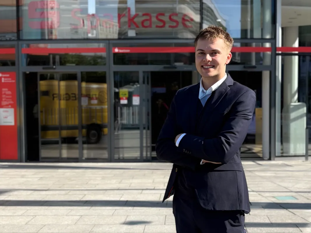 Junger Sparkassenmitarbeiter kurz nach der Ausbildung steht vor dem Sparkassen-Karree in Hagen.